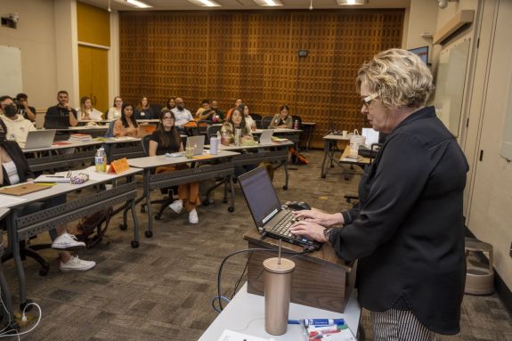 woman types on keyboard in front of a class 