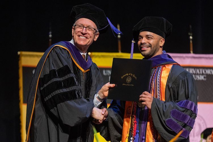Dean Schwartz presents a diploma to a law school graduate